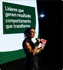 Cecília no palco com o tema Líderes que geram resultado, comportamento que transforma